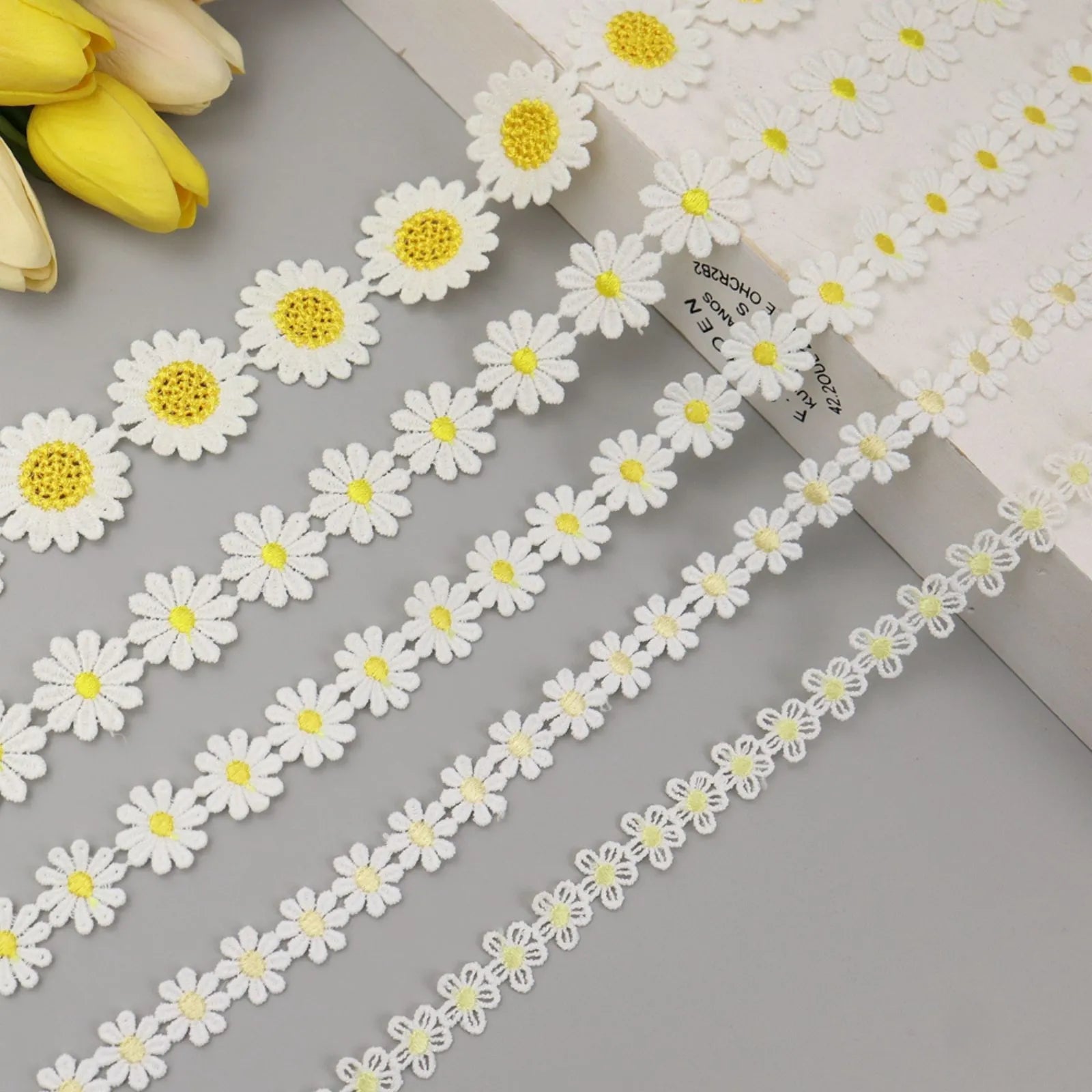 Close-up of yellow embroidered daisy flower lace trim showing intricate floral embroidery and soft texture