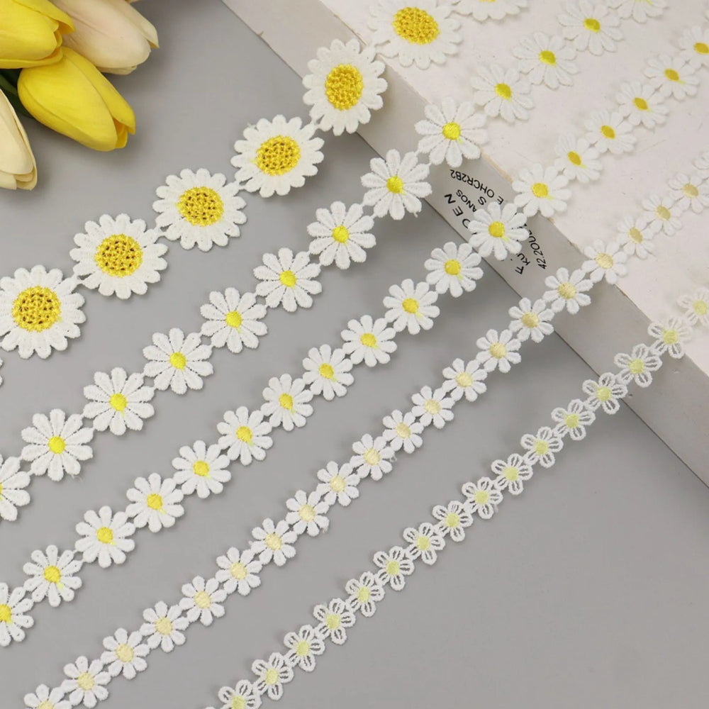 Close-up of yellow embroidered daisy flower lace trim showing intricate floral embroidery and soft texture